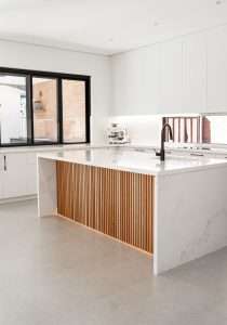 Architectural kitchen with flutted wooden panels and white marble stone benchtop island