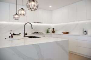 White kitchen with finger pull handles and stone bench